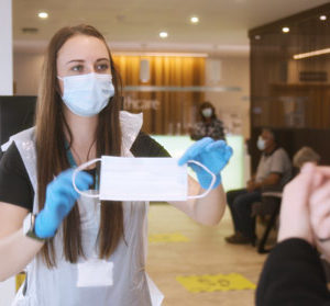 girl handing face mask to hospital attendee
